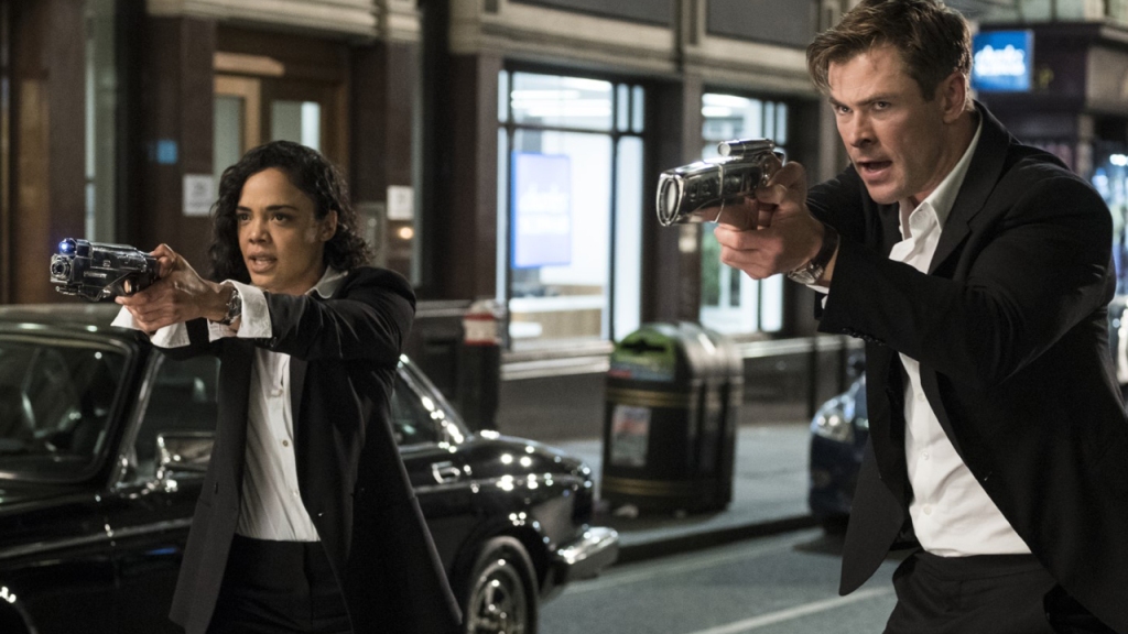 Agent M (Tessa Thompson) and Agent H (Chris Hemsworth) aiming their weapons at something. 