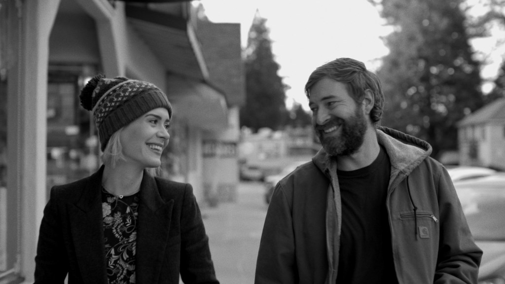 Amanda (Sarah Paulson) and Jim (Mark Duplass) walking down a street smiling at each other.