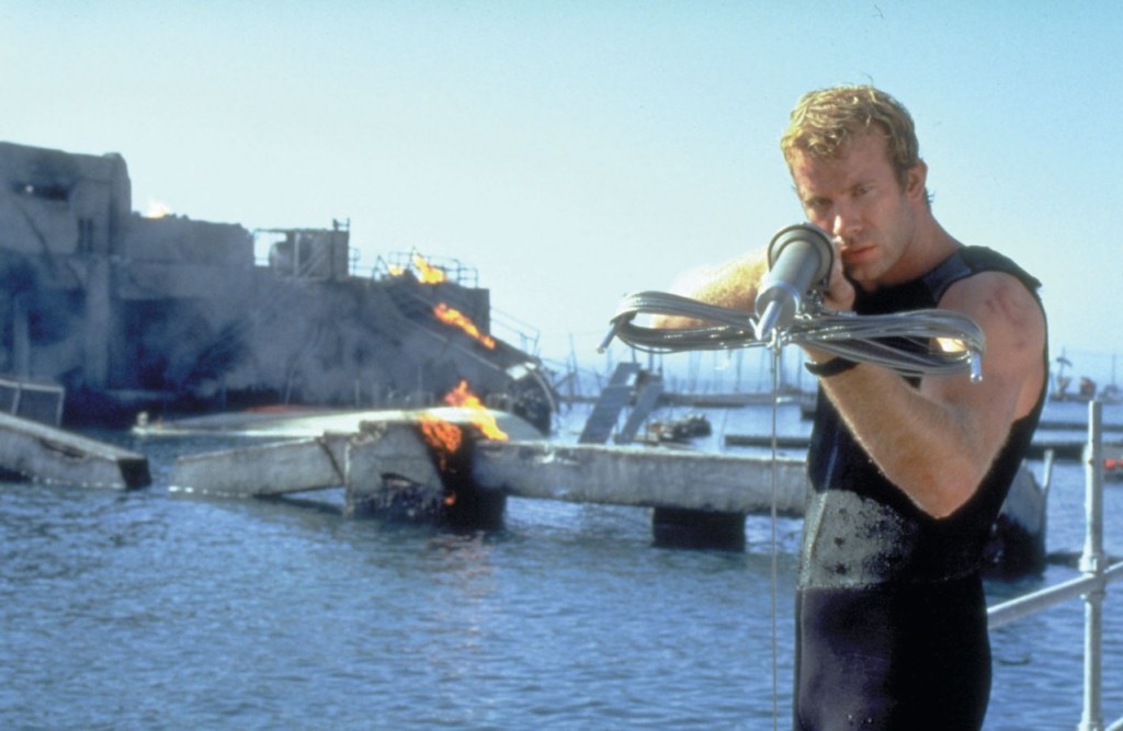 Carter (Thomas Jane) aiming a harpoon at a shark.