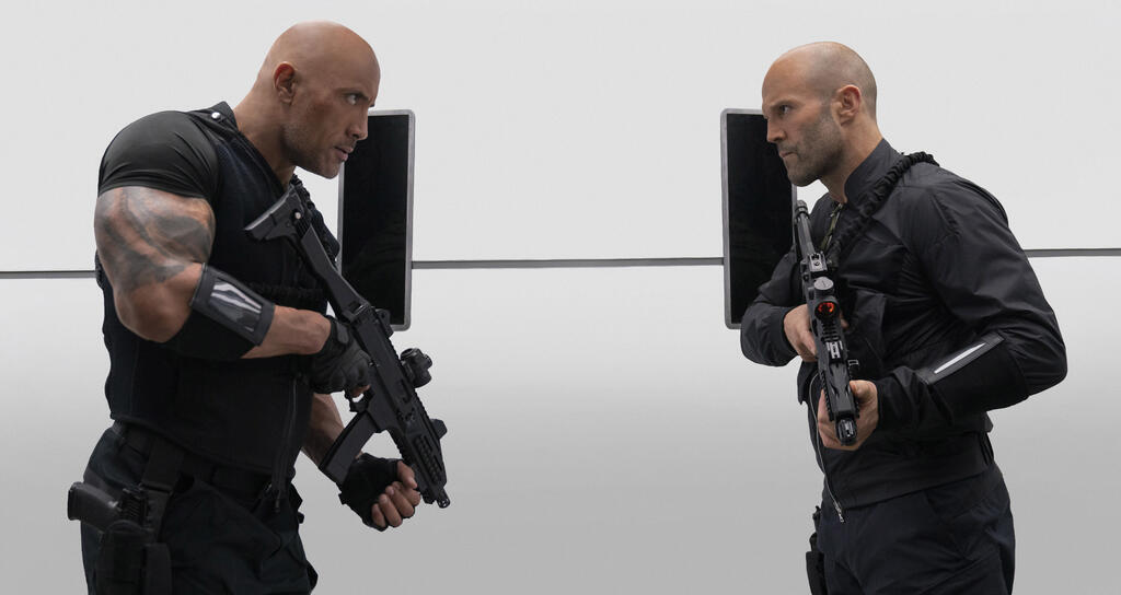 Hobbs (Dwayne Johnson) and Shaw (Jason Statham) facing each other with automated weapons in hand.
