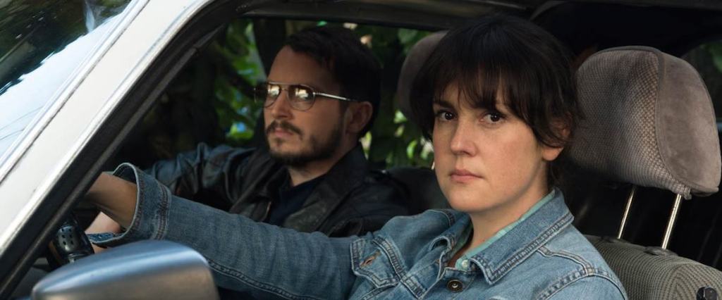 Tony (Elijah Wood) and Ruth (Melanie Linskey) observing something from the car.
