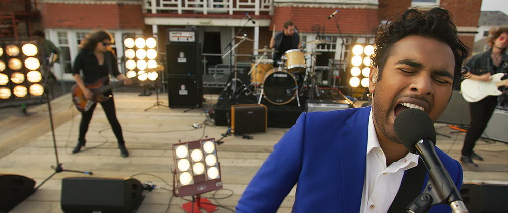 Jack (Himesh Patel) singing at a concert he gives on a rooftop.