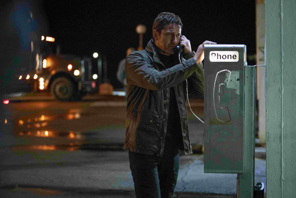 Mike Banning (Gerard Butler) using a payphone, looking disheveled.
