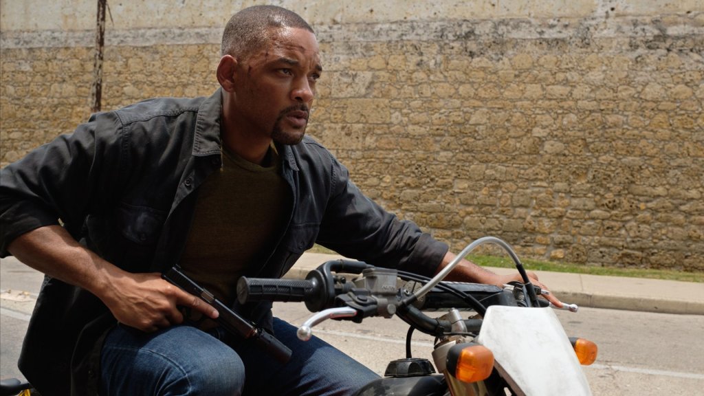 Henry (Will Smith) on a motorcycle holidng a gun.