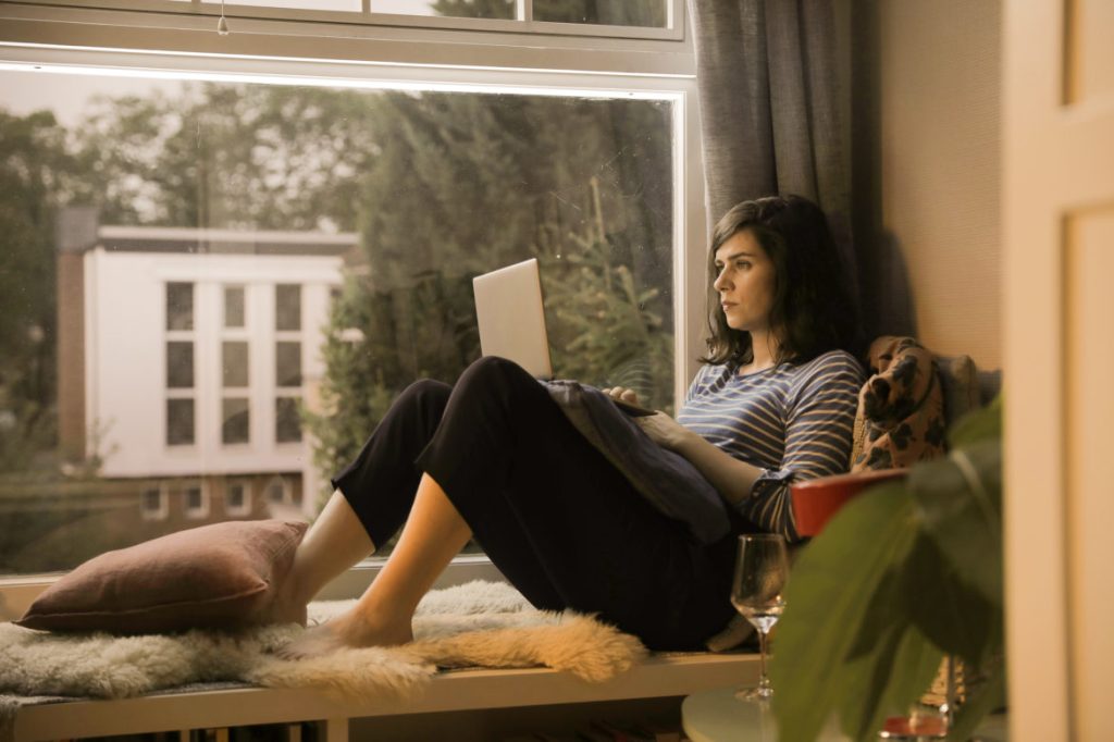 Emmi (Nora Tschirner) sitting on the windwo sill with her computer on her lap.