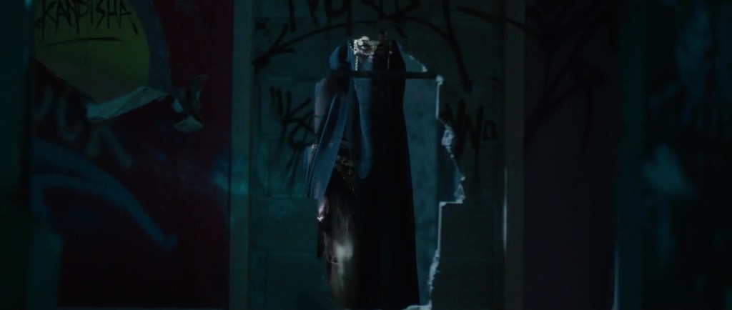 Kandisha (Mériem Sarolie) - a veiled woman - seen through a hole in the wall.