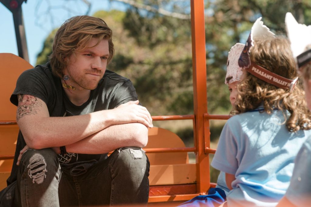 Dave (Alexander England) talking to a couple of children.