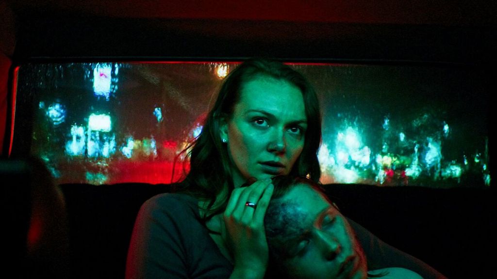 Laura (Andi Matichak) cradling her son David (Luke David Blumm) in a taxi. He looks sick and bruised.
