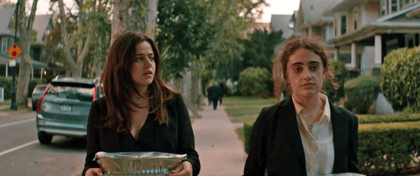 Maya (Molly Gordon) and Danielle (Rachel Sennott) carrying some food to the car.