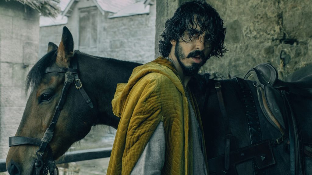A dishevelled Gawain (Dev Patel) about to get on his horse.