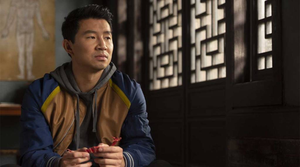 Shaun (Simu Liu) looking pensive, holding an origami dragon.