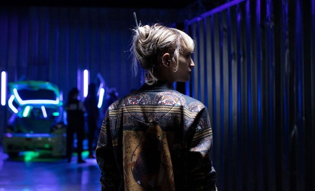 Alexia (Agathe Rousselle) walking through the car show.