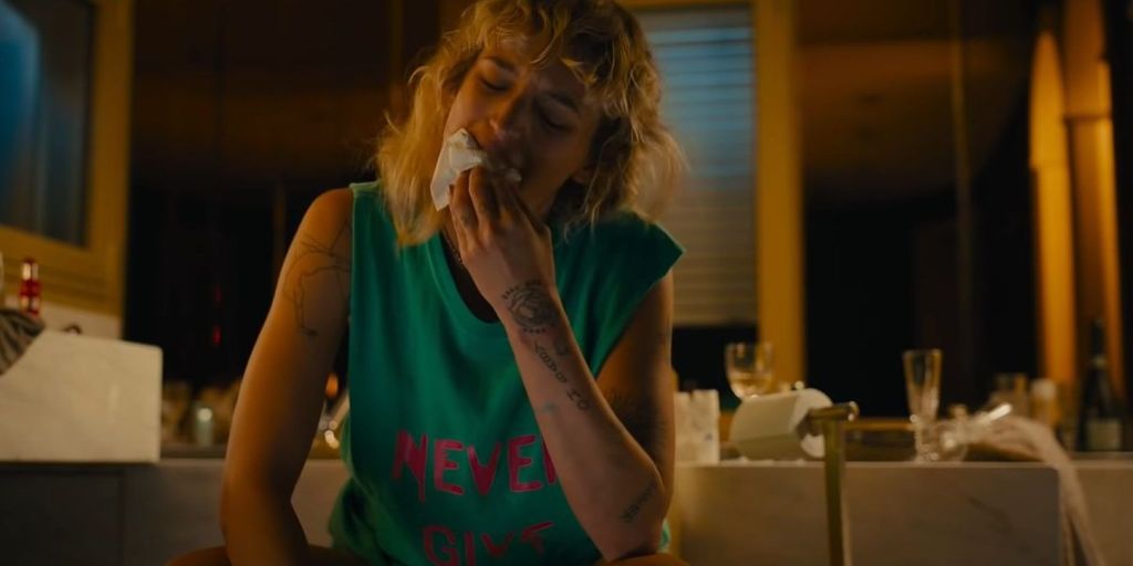 Alexia (Agathe Rousselle), kneeling on the bathroom floor, wiping her mouth with a tissue.