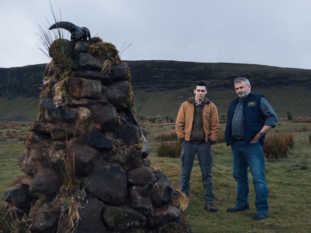 Eugene (Jack Rowan) and Francie (Nigel O'Neill) looking at the cairn.