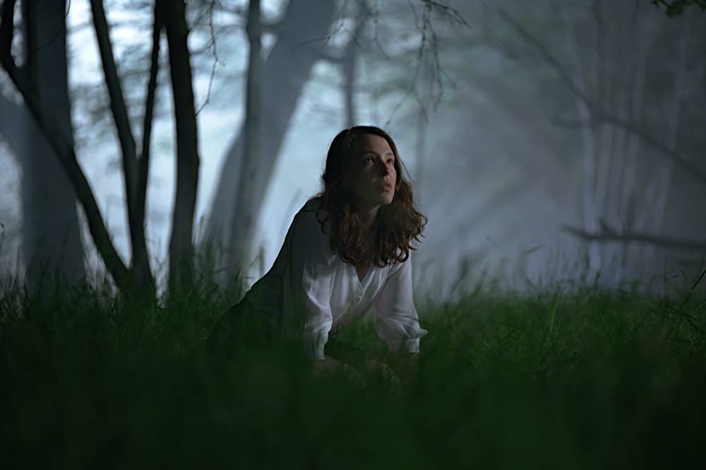 Cadi (Annes Elwy) kneeling in the grass.