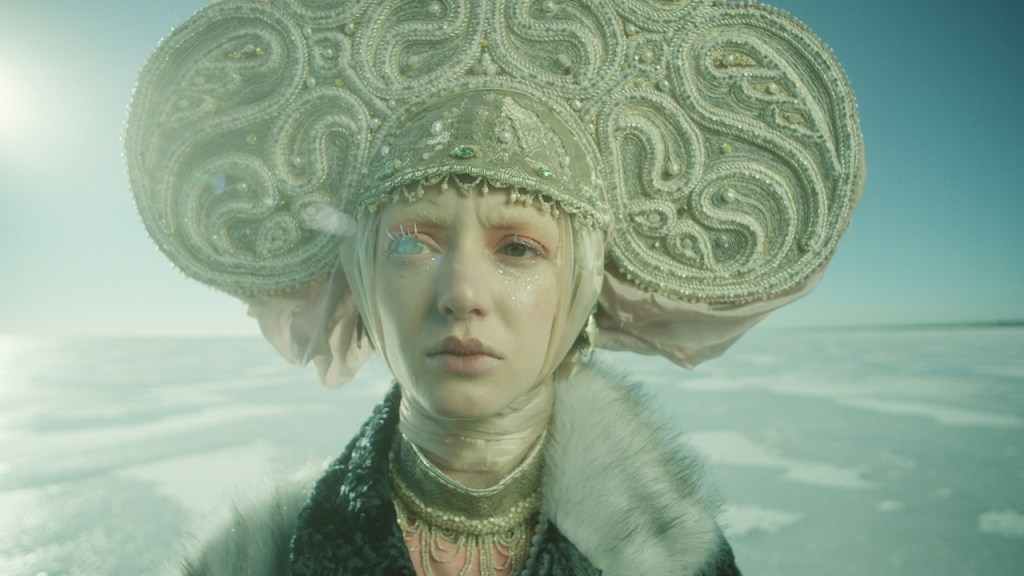Polina (Alina Korol) standing in an icy landscape wearing a fancy headdress.