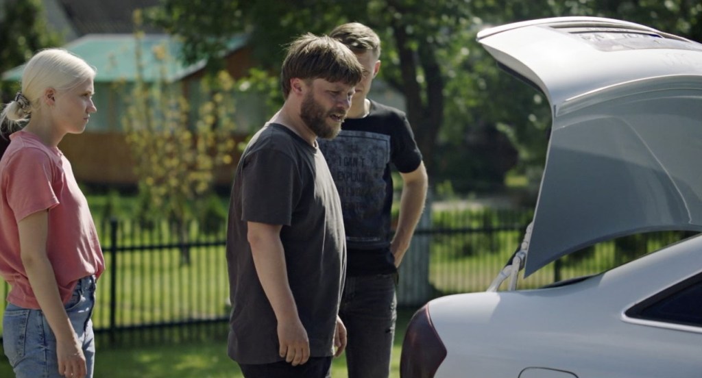 Indre (Gabija Bargailaite) and Paulius (Giedrius Kiela) about to buy a car, looking at its trunk.