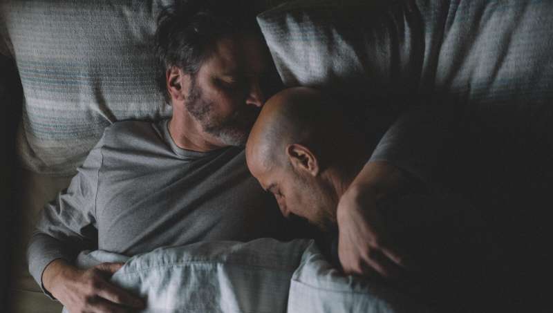 Sam (Colin Firth) and Tusker (Stanley Tucci) cuddling in bed.