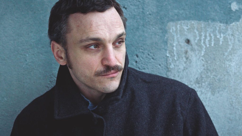 Hans (Franz Rogowski) leaning against a wall.