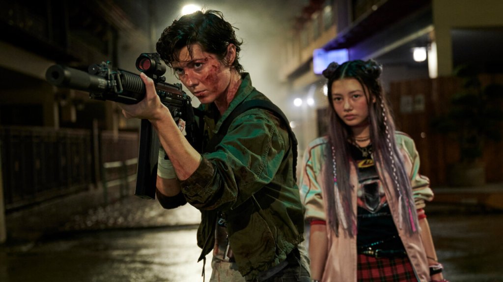 Kate (Mary Elizabeth Winstead) aiming an assault rifle with Ani (Miku Patricia Martineau) behind her.