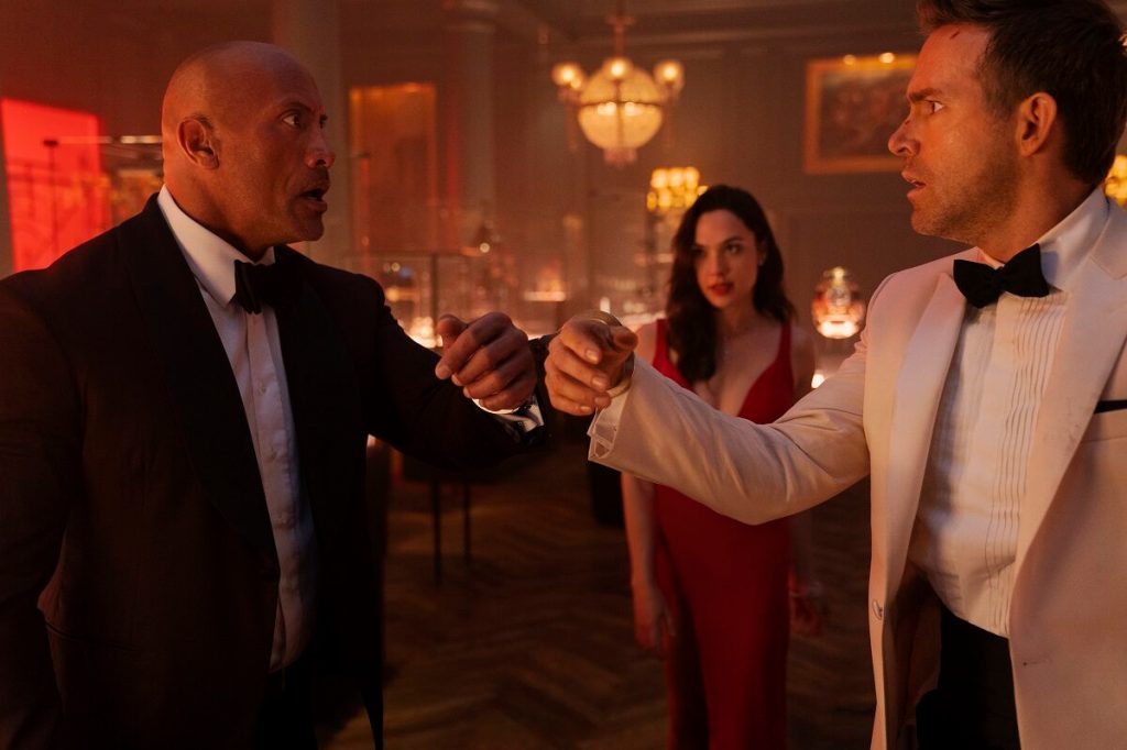 Hartley (Dwayne Johnson) and Booth (Ryan Reynolds) handcuffed together by The Bishop (Gal Gadot). 