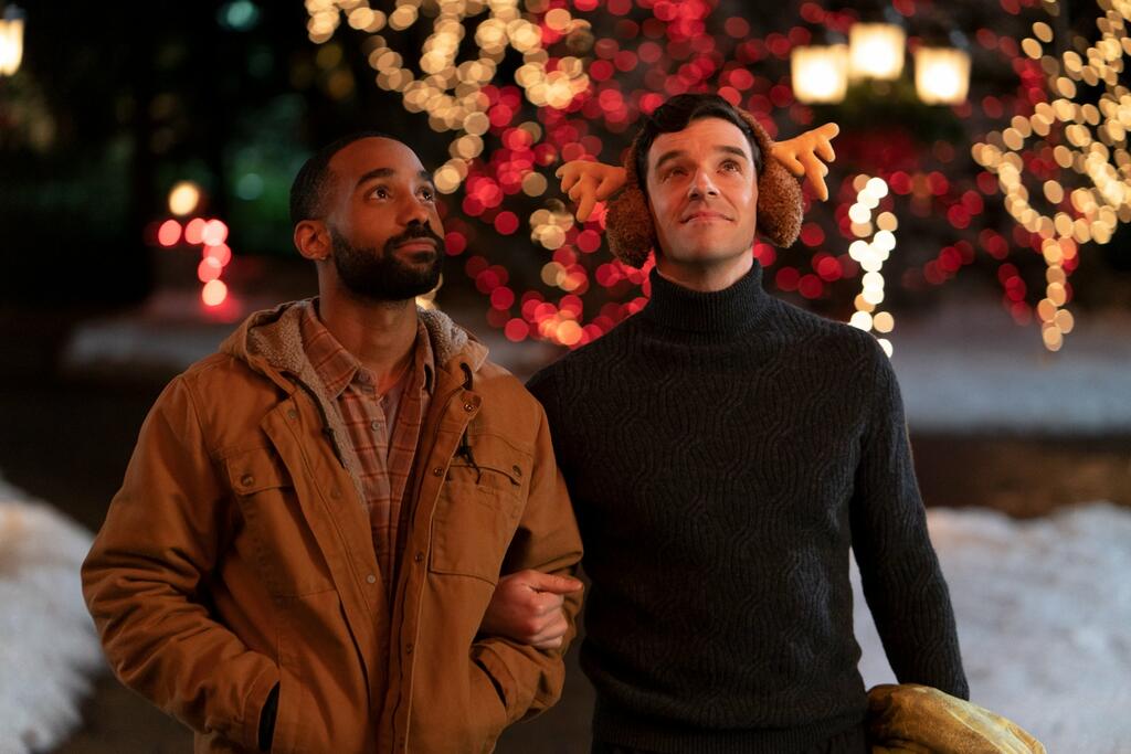 Nick (Philemon Chambers) and Peter (Michael Urie) walking through the snow and Christmas lights together.