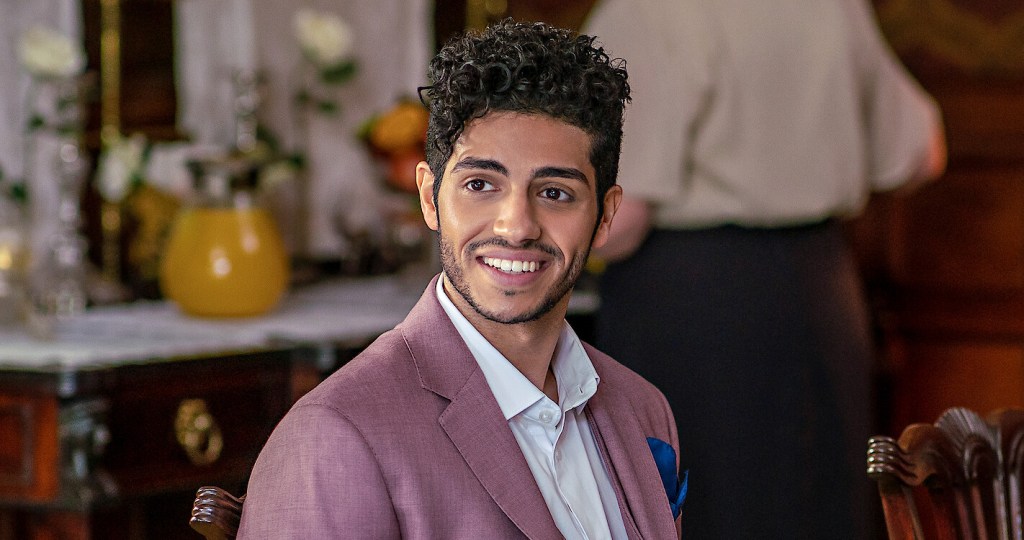 Prince Thomas (Mena Massoud) at the breakfast table in his castle.