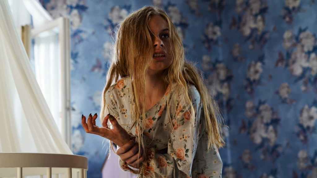 Tinja (Siiri Solalinna) holding her hand that looks a bit like a claw. She has a feral facial expression.