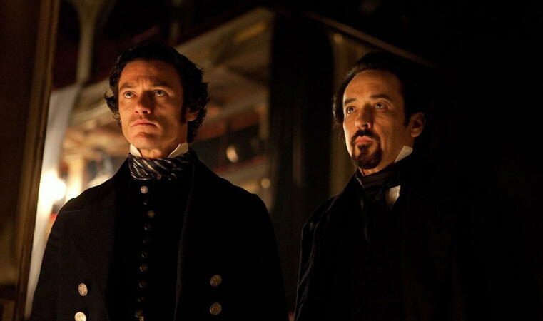 Detective Fields (Luke Evans) standing next to Edgar Allan Poe (John Cusack)