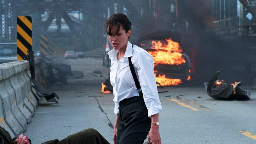 Illeana (Angelina Jolie) standing at the site of a car accident, a burning car behind her.