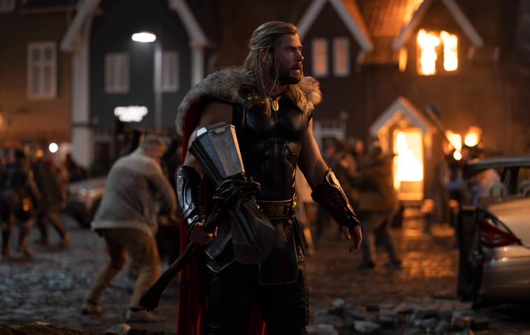 Thor (Chris Hemsworth) standing in New Asgard that has turned into a battlefield.