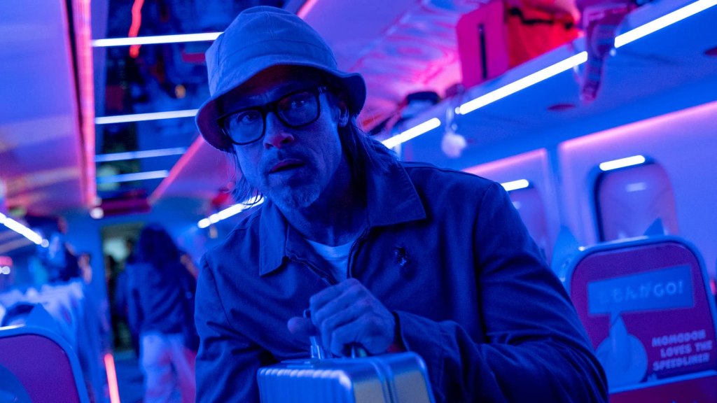 Ladybug (Brad Pitt) walking carefully through the train, clutching a suitcase.