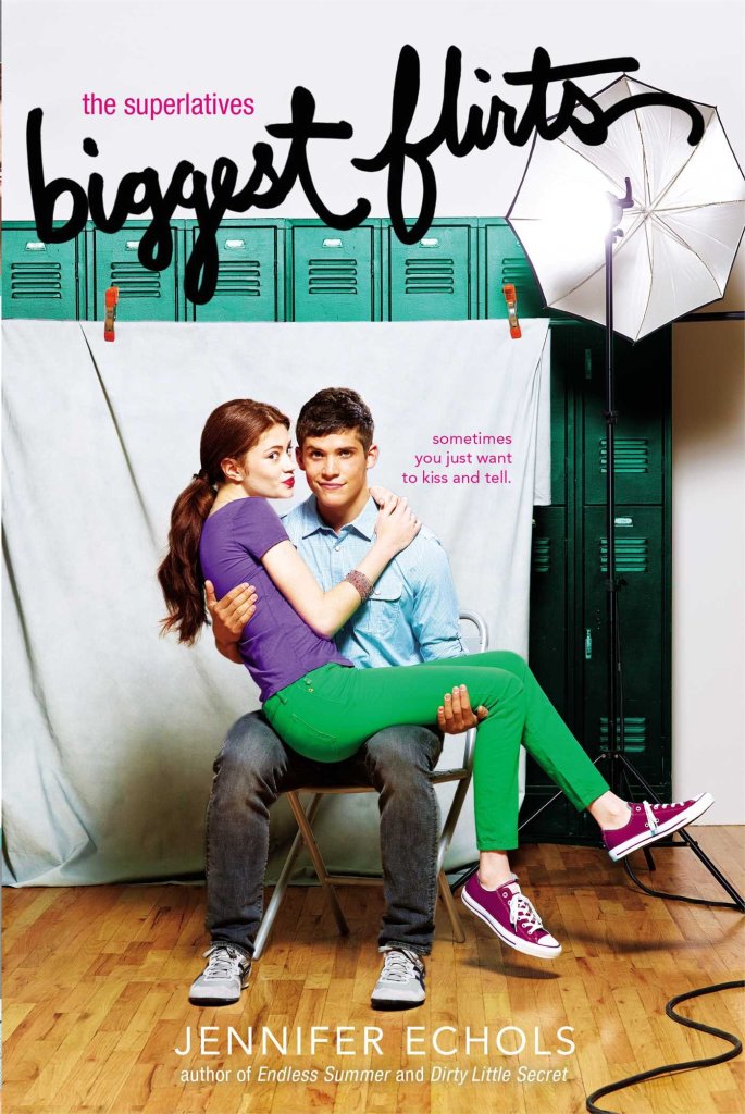 The book cover showing a boy and a girl posing for a photo in front of school lockers. She is sitting on his lap, making a kissy mouth.
