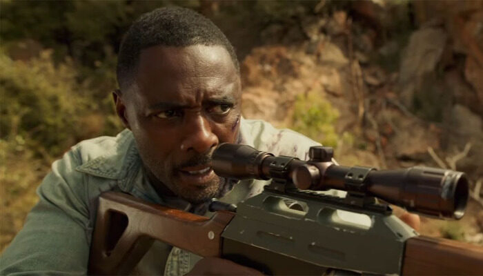 Nate (Idris Elba) looking through the scope of a rifle.