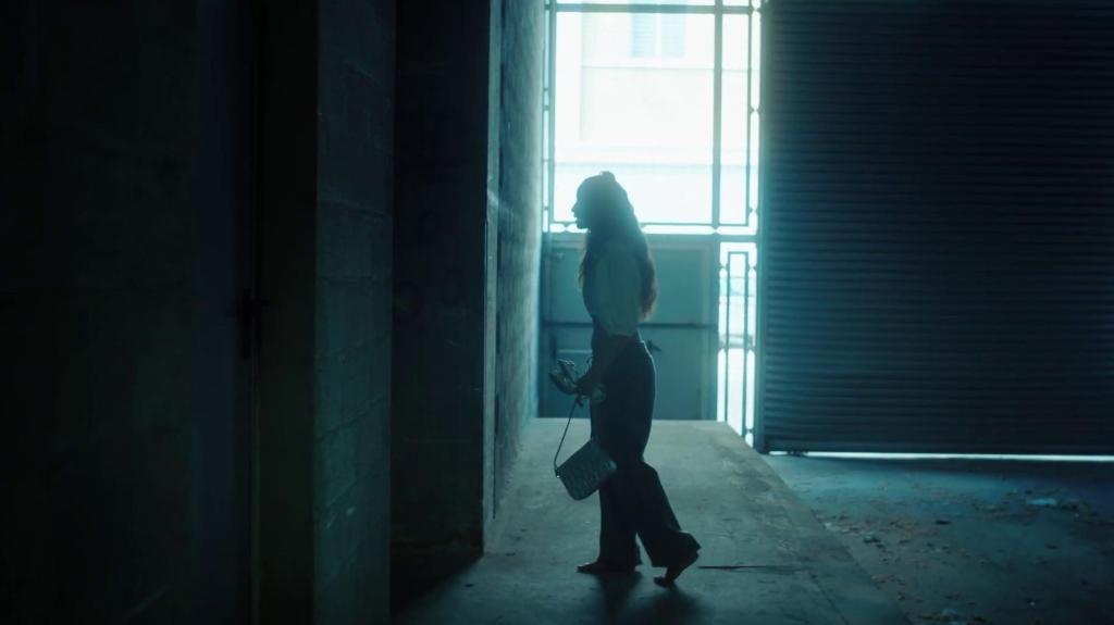 Nora (Oulaya Amamra) walking in a dark, empty warehouse.