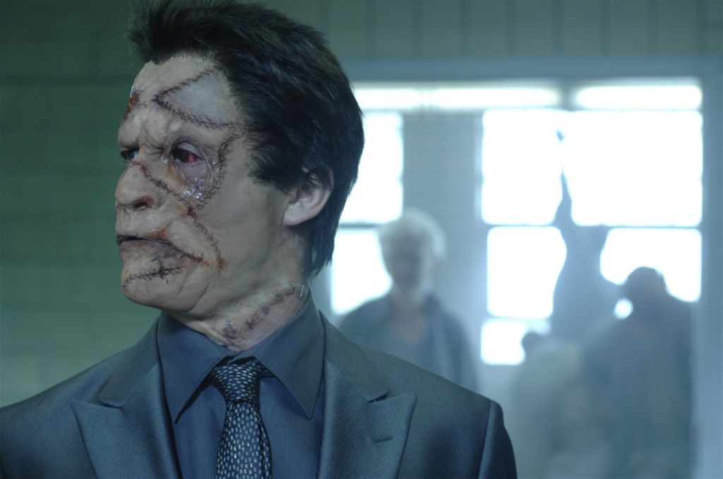 Jigsaw (Dominic West), his face marred by scars that crisscross all over.
