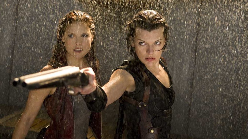 Alice (Milla Jovovich) aiming a gun in the rain, with Claire (Ali Larter) behind her.