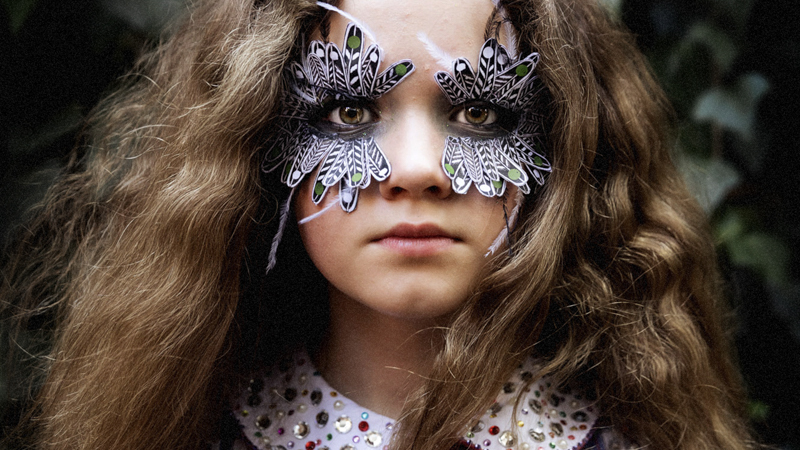 Blaze (Julia Savage) with feather-like make-up glued around her eyes.