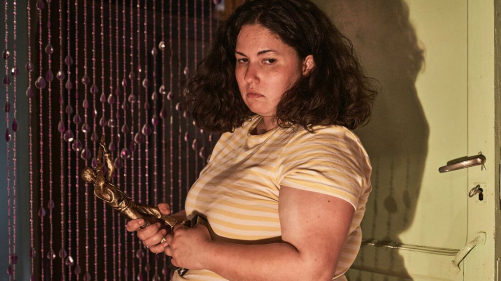 Sara (Laura Galán) holding a golden statue.