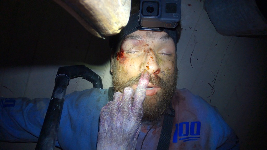 Shawn (Joseph Winter) lying unconscious on the floow, a monster finger in his nose.