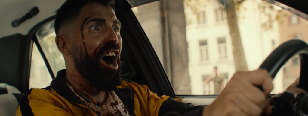 Noah (Dimitri 'Vegas' Thivaios) driving. He is screaming, his face is bloody.