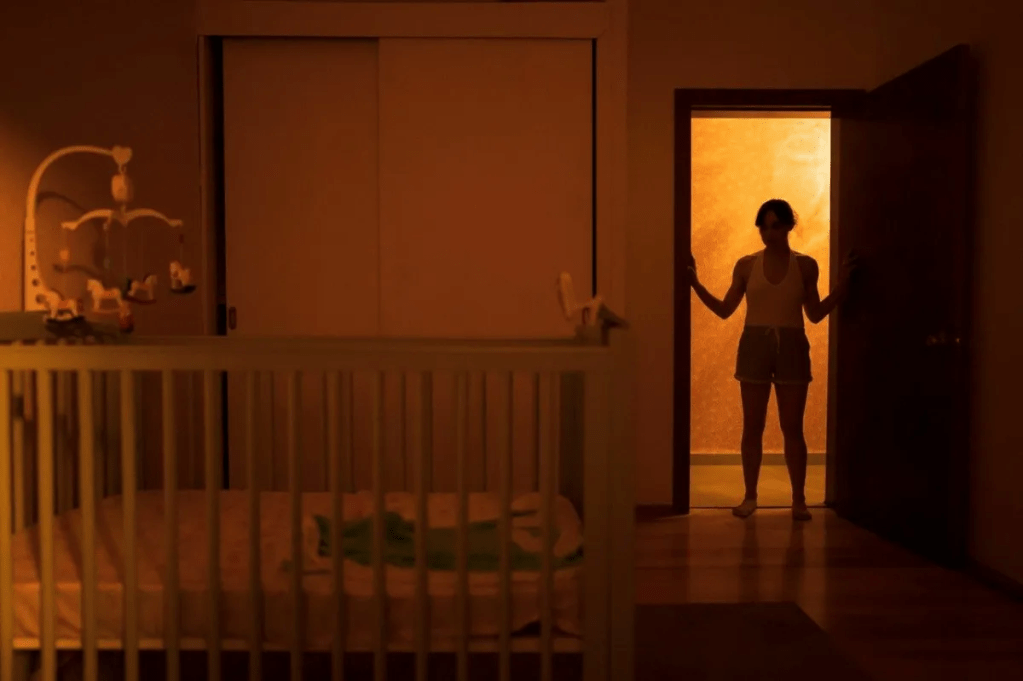 Valeria (Natalia Solián) standing in the door of the children's room, looking at an empty crib.