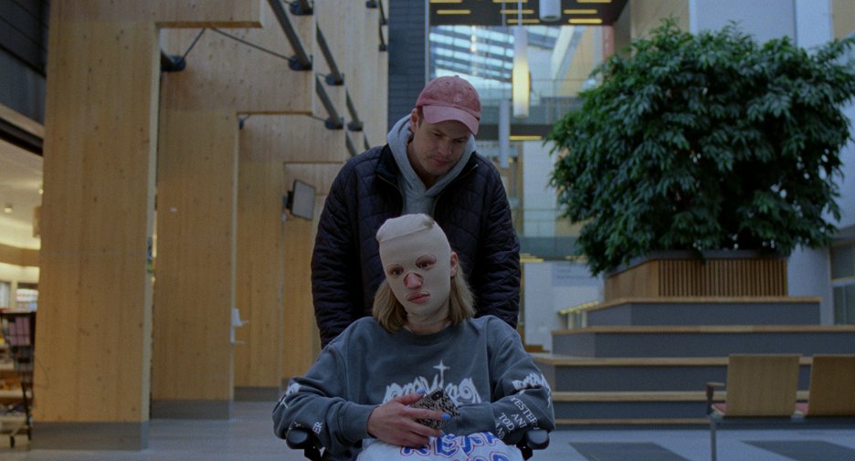 Thomas (Eirik Sæther) pushing Signe (Kristine Kujath Thorp) in her wheelchair, her face bandaged.
