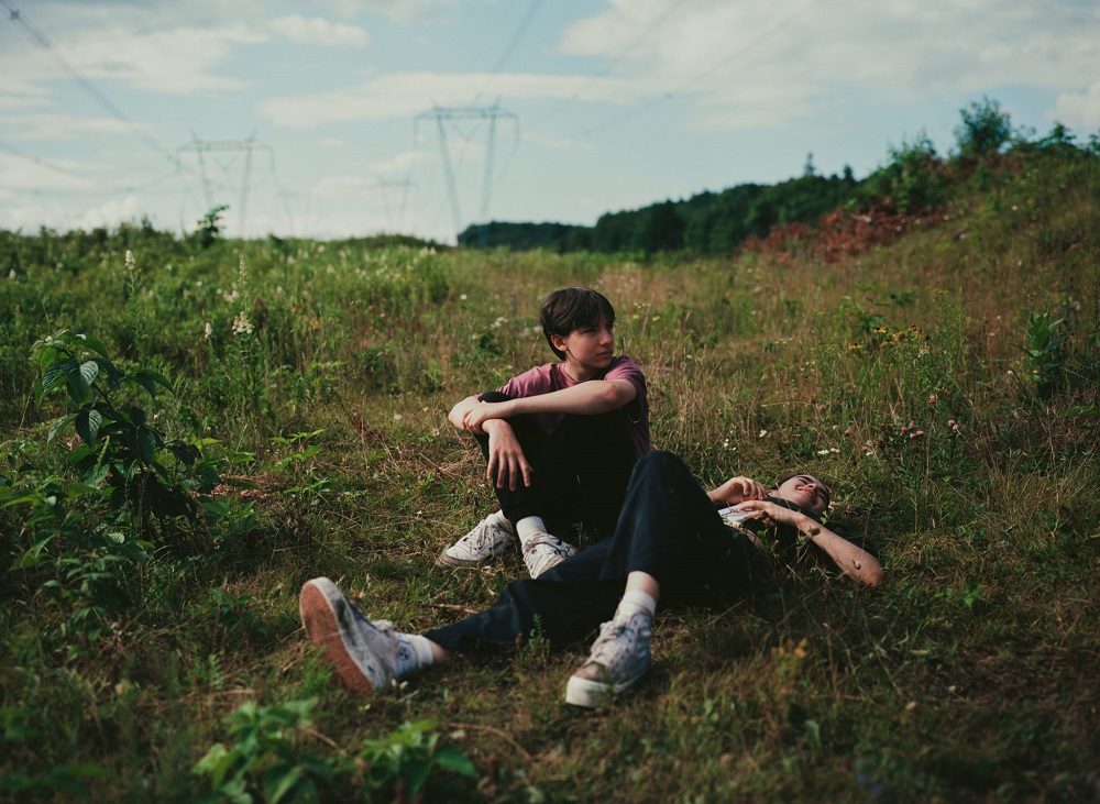 Bastien (Joseph Engel) and Chloe (Sara Montpetit) chilling in the grass.