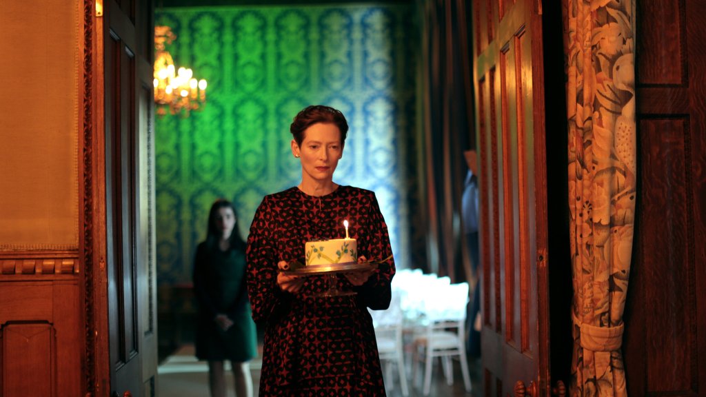 Julie (Tilda Swinton) carrying a birthday cake with a single candle.