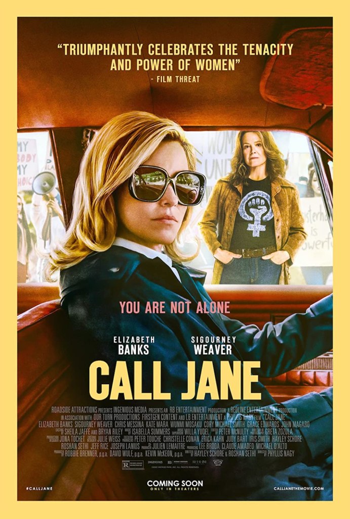 The film poster showing Joy (Elizabeth Banks) sitting in a car. Behind the car is Virginia (Sigourney Weaver) surrounded by feminist protestors.