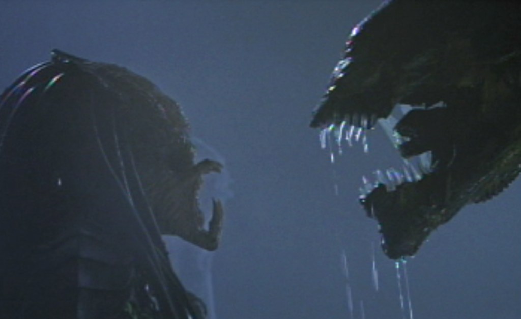 The Predator and the Alien squaring off, snarling at each other.