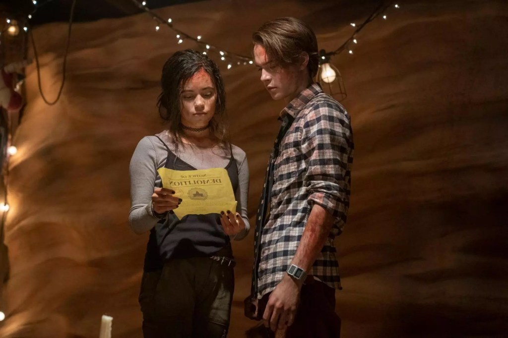 Phoebe (Jenna Ortega) and Cole (Judah Lewis) looking at a flyer together.