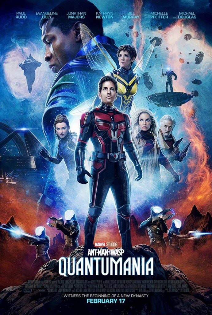 The film poster showing Ant-Man/Scott (Paul Rudd) standing front and center with the other main characters arranged behind him. THey are all standing in front of a space-like background with armed figures and floating rocks. 