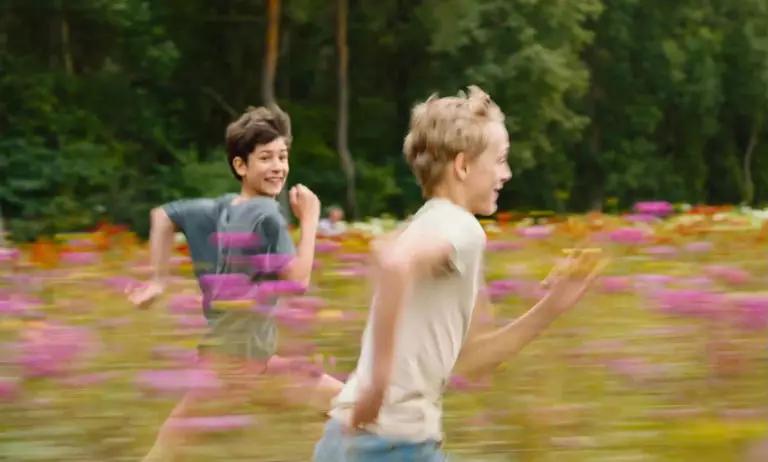 Léo (Eden Dambrine) and Rémi (Gustav De Waele) running through a flower field.
